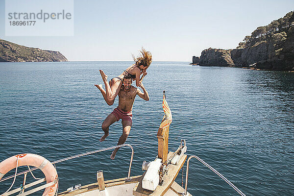 Mann und Frau springen im Urlaub vom Boot ins Meer