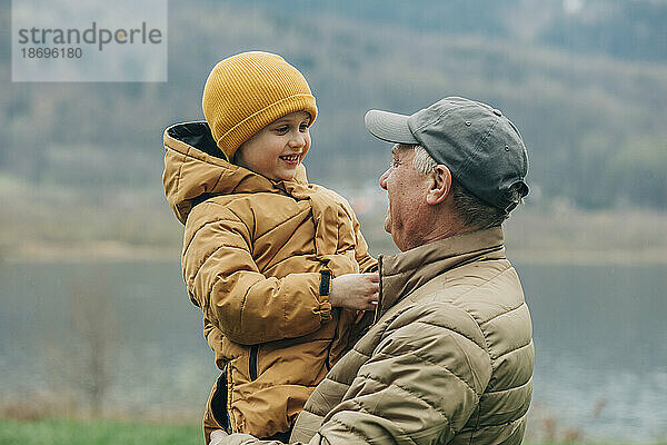 Großvater trägt Enkel in warmer Kleidung