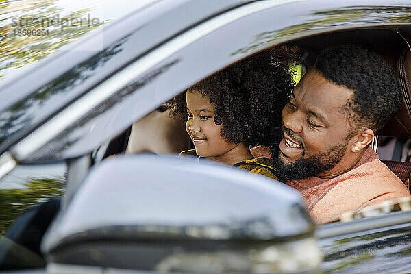Lächelnder Mann genießt Roadtrip mit Tochter im Auto