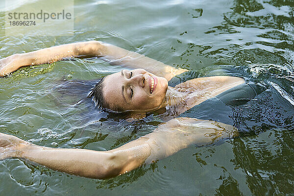 Lächelnde Frau schwimmt auf dem Wasser im See