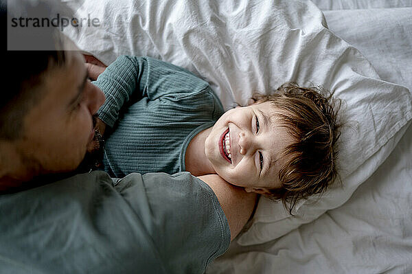 Father spending leisure time with son on bed at home