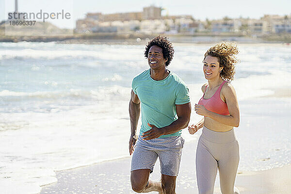 Lächelndes Paar läuft am Strand