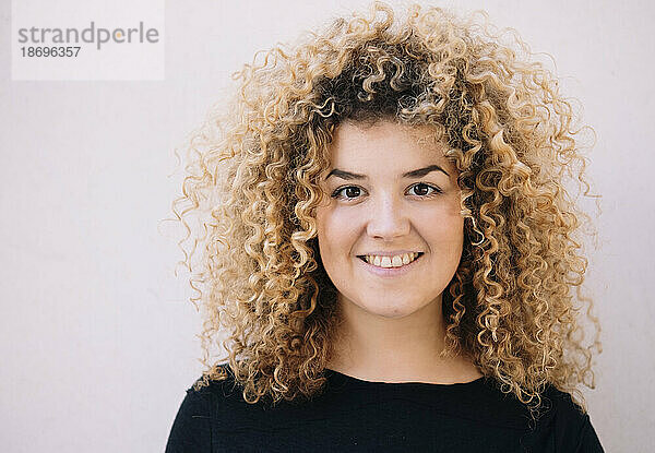 Smiling woman with curly hair against white background