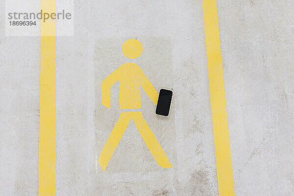 Wanderschild mit Mobiltelefon auf dem Boden in der Fabrik