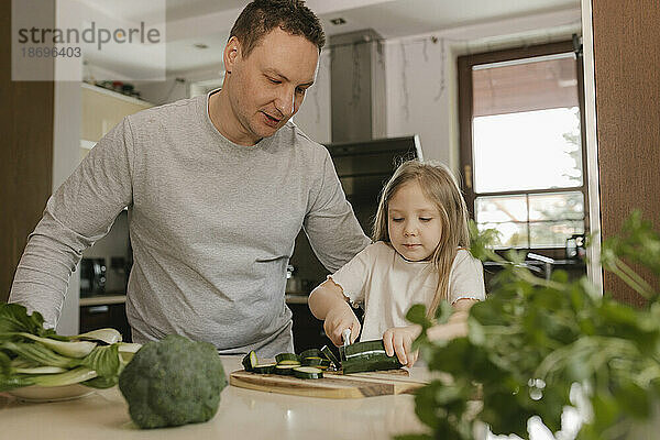 Vater bringt Tochter bei  Zucchini in der heimischen Küche zu schneiden