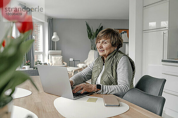 Ältere Frau kauft zu Hause per Laptop online ein