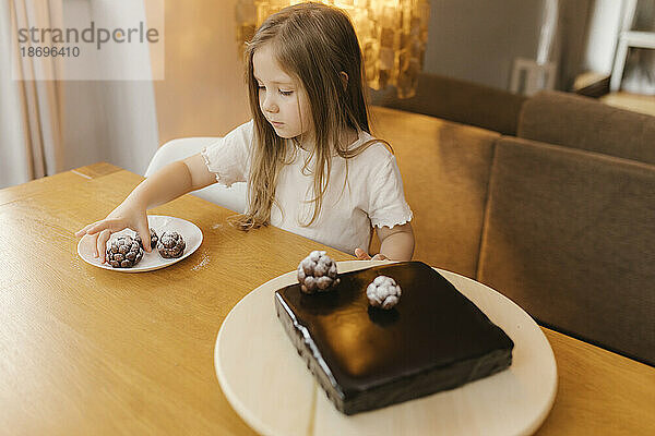 Girl decorating chocolate cake with pine cones at home