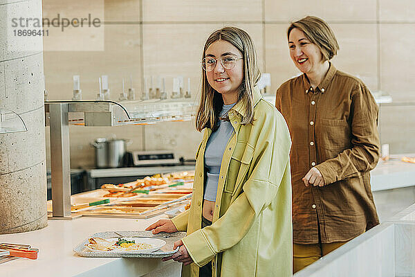 Lächelnde Mutter und Tochter essen am Buffet im Café