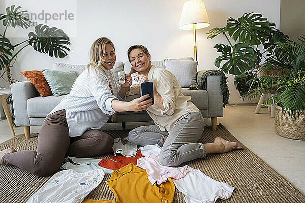 Schwangere Tochter macht Selfie mit Mutter  die zu Hause Babysocken hält
