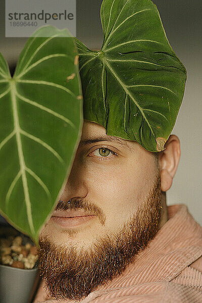 Junger Mann mit Bart am Pflanzenblatt