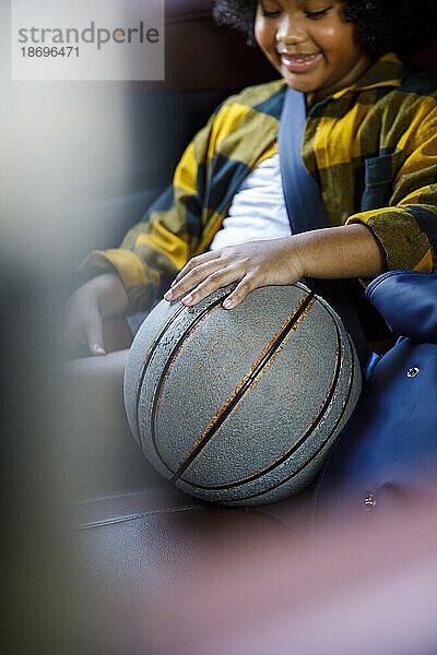 Smiling girl sitting with basketball in car