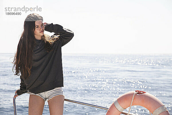 Teenager-Mädchen mit der Hand im Haar auf einem Boot  das im Meer segelt