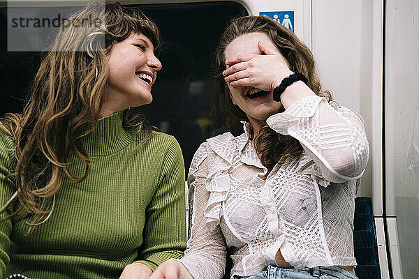 Lächelnde Frau  die von ihrer Freundin in der U-Bahn lacht