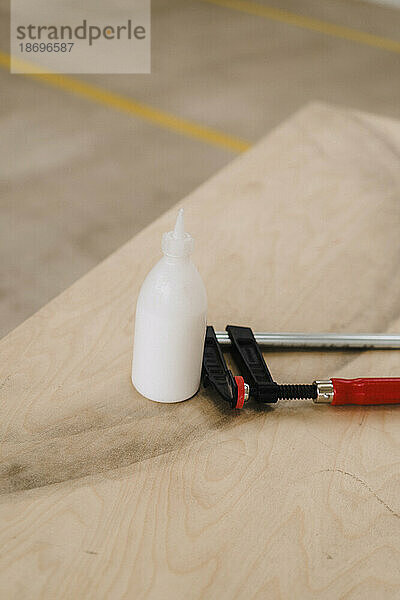Glue bottle with clamp on wooden table in carpentry factory