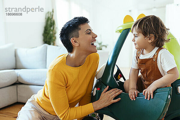 Happy woman with son in toy car at home