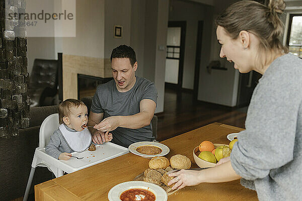 Vater füttert kleinen Jungen zu Hause am Esstisch