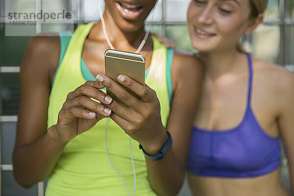Frau teilt Smartphone mit Freund in Sportkleidung