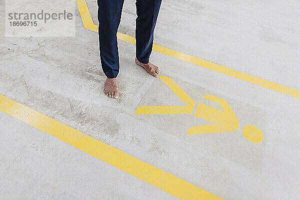 Businessman standing barefoot by sign on floor in factory