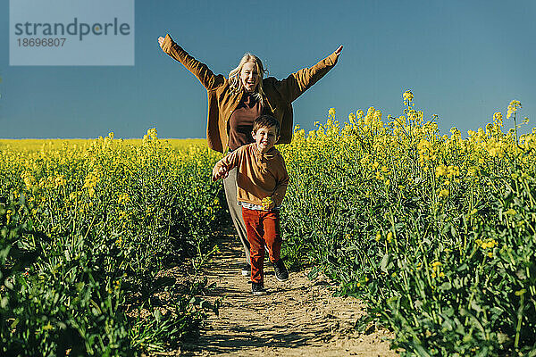 Playful mother and son running in rapeseed field