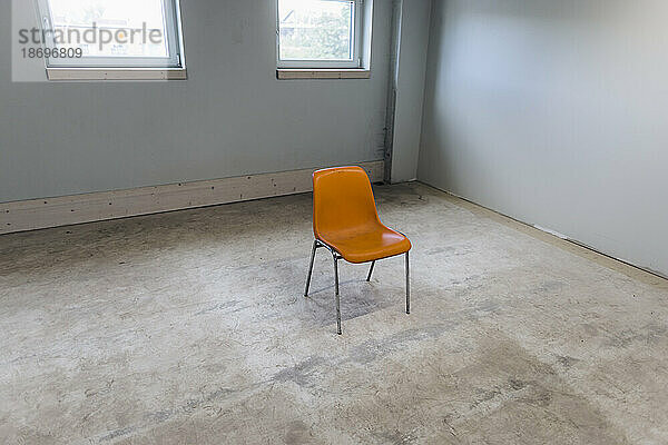 Orangefarbener Stuhl im leeren Raum
