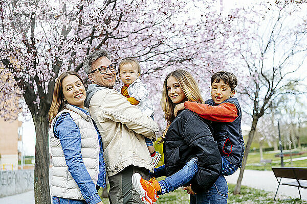 Glückliche Familie steht vor dem Kirschblütenbaum