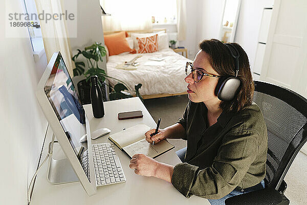 Freiberufler mit kabellosen Kopfhörern bereitet Strategie im Heimbüro vor