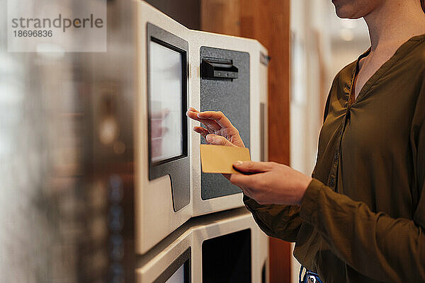 Frau hält Kreditkarte in der Nähe eines Geldautomaten