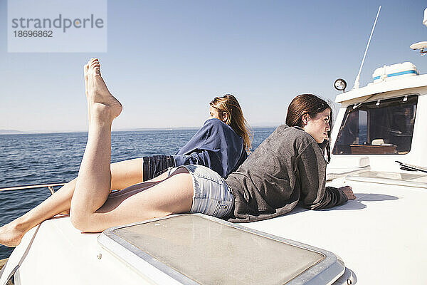 Frauen liegen im Urlaub zusammen auf Bootsdeck