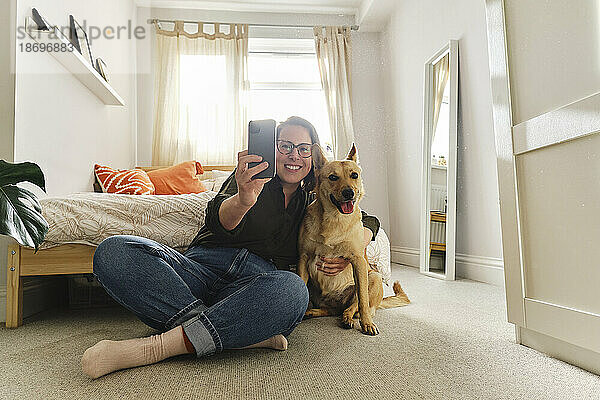 Frau macht Selfie mit Hund  der zu Hause sitzt