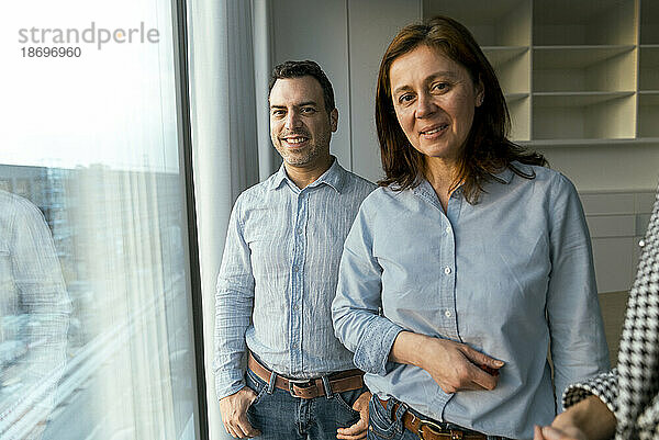 Portrait of smiling businesswoman with colleague at the window in office