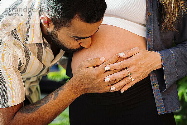 Mann küsst Bauch einer schwangeren Frau