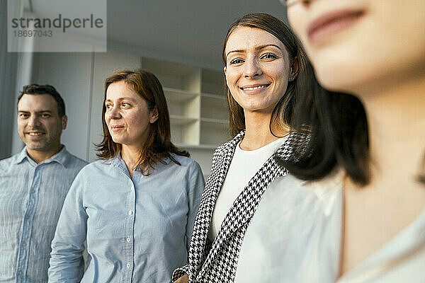 Porträt einer lächelnden Geschäftsfrau mit Kollegen im Büro