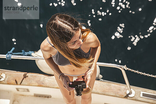 Junge Frau hält Kamera auf Yacht