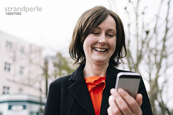 Lächelnde Frau im Blazer mit Smartphone