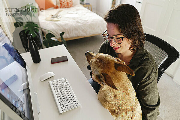 Freiberufler mit Hund sitzt am Schreibtisch im Heimbüro