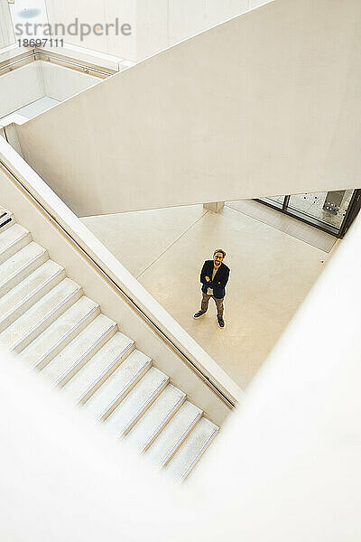 Businessman standing in corridor seen from staircase