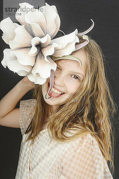 Blond girl sticking out tongue and holding flower