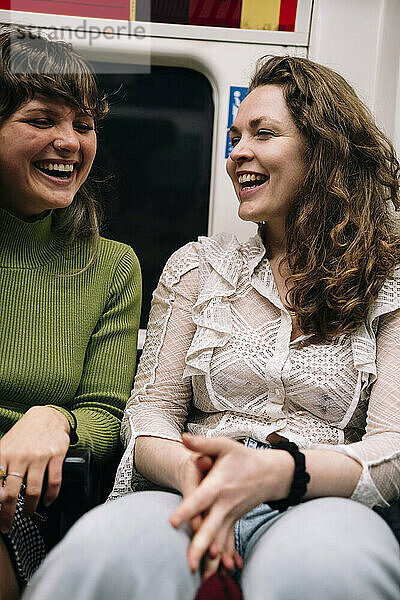 Happy female friends sitting in subway