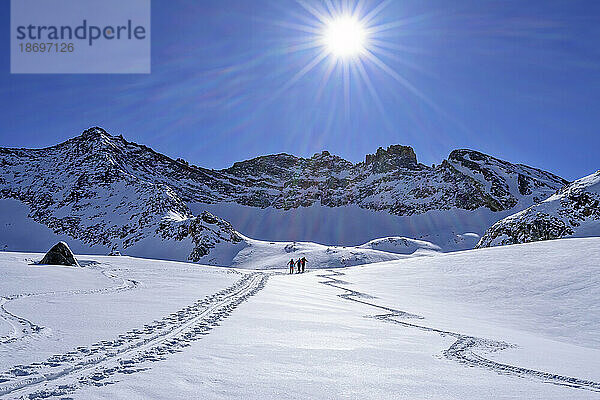 Österreich  Tirol  Sonne scheint über Skifahrern  die durch den Schnee am Hollensteinkar fahren
