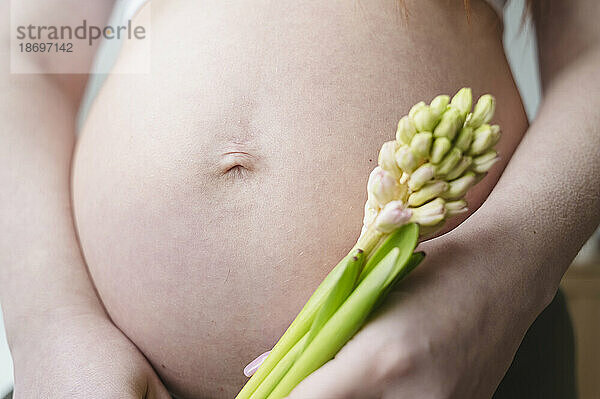 Schwangere Frau hält Blumen in der Hand
