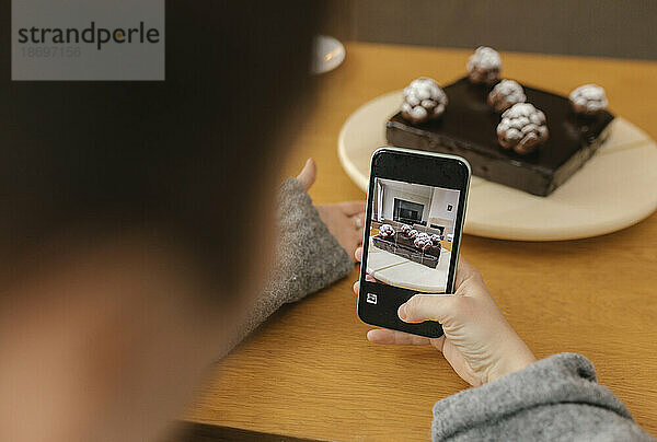 Frau fotografiert hausgemachten Kuchen mit Smartphone zu Hause