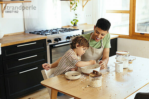 Mutter und Sohn bereiten Essen am Esstisch in der Küche zu