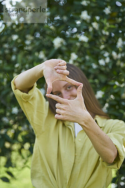 Frau macht Fingerrahmen im Garten