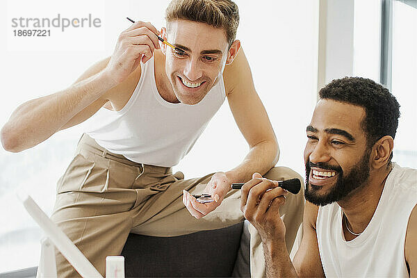 Happy friends applying make-up with brush
