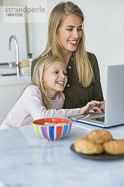 Lächelnde Tochter lernt mit Mutter zu Hause  Laptop zu benutzen