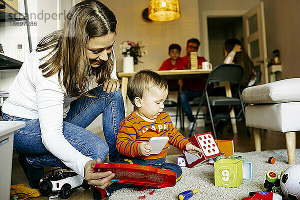 Mutter kauert neben ihrem Sohn und spielt zu Hause mit Spielzeug