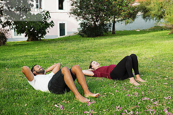 Schwangere Frau trainiert mit Mann  der auf Gras liegt