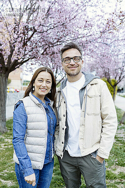 Lächelndes Paar  das zusammen vor dem Kirschblütenbaum steht