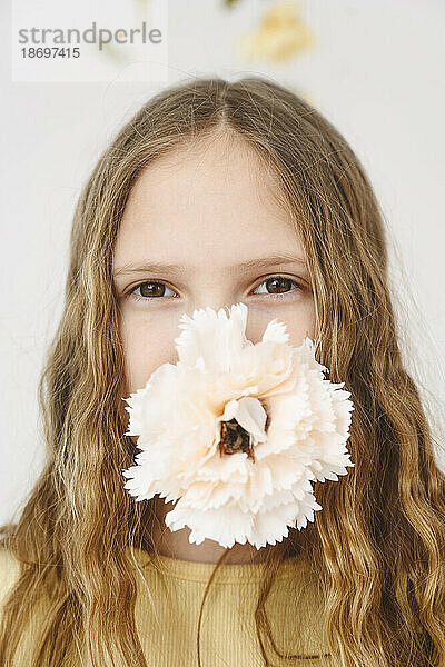 Blond girl carrying flower in mouth