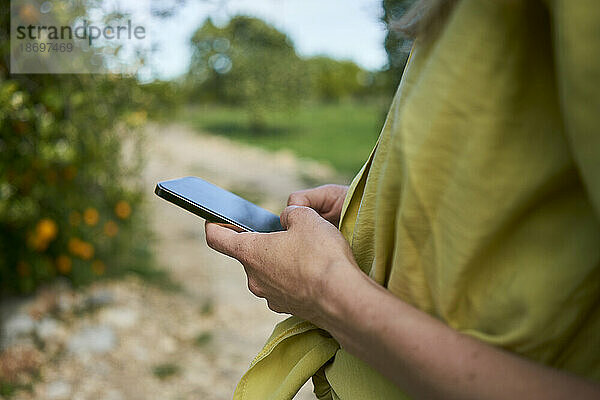 Frau schreibt Textnachrichten per Smartphone im Garten
